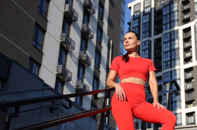 Photo of Beautiful woman in sportswear before running near buildings outdoors, low angle view