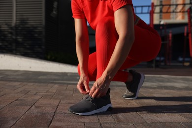 Photo of Woman tying shoelaces before running outdoors, closeup