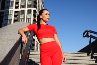 Photo of Beautiful woman in sportswear before running on stairs outdoors, low angle view