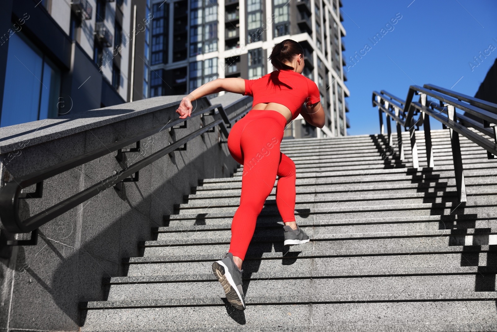 Woman in sportswear running up on stairs outdoors, low angle view Photo of Woman in sportswear running up on stairs outdoors, low angle view