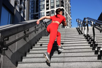 Photo of Woman in sportswear running up on stairs outdoors, low angle view