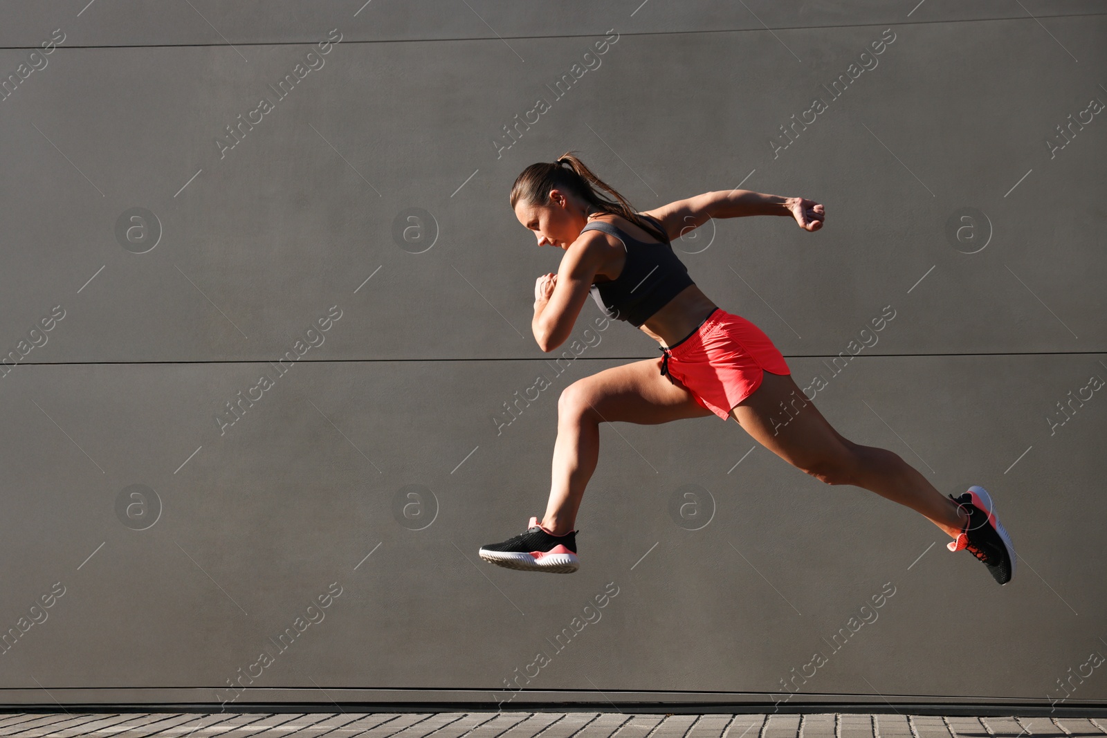 Woman in sportswear running near building outdoors, space for text Photo of Woman in sportswear running near building outdoors, space for text