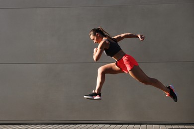 Photo of Woman in sportswear running near building outdoors, space for text