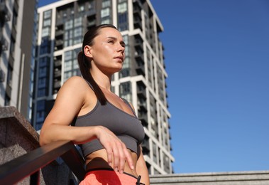 Photo of Beautiful woman in sportswear before running on stairs outdoors, low angle view