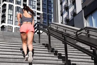 Photo of Woman in sportswear running up on stairs outdoors, low angle view