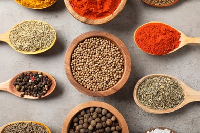Photo of Different aromatic spices on gray textured table, flat lay