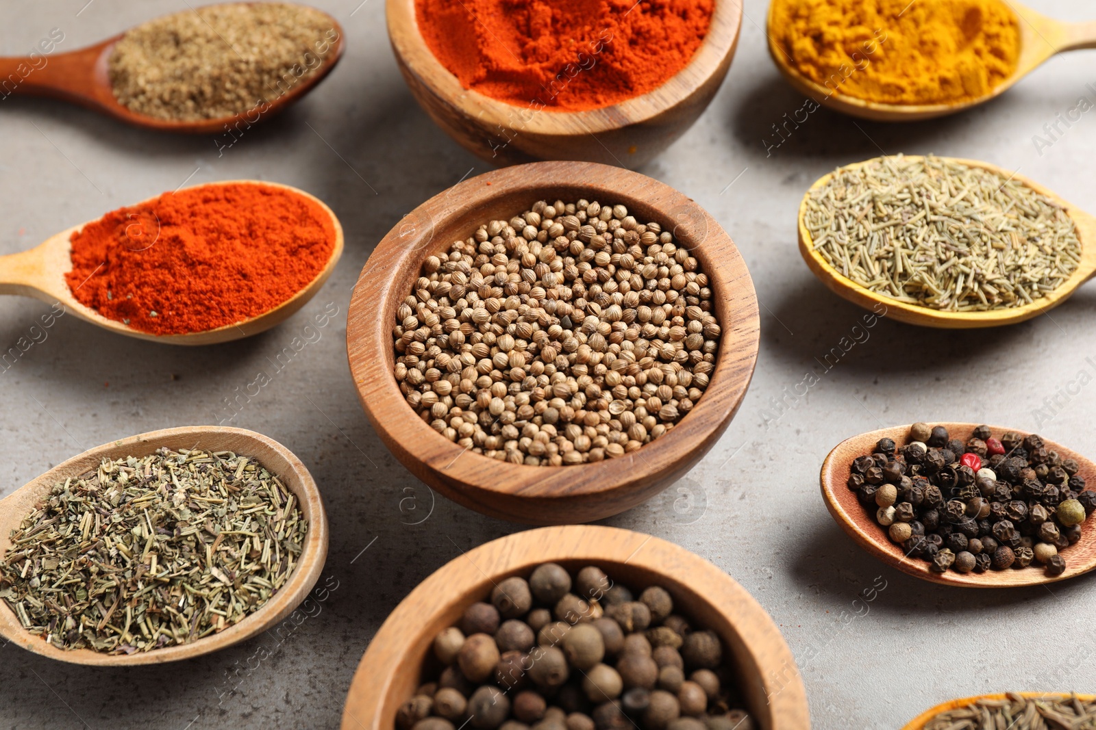Photo of Different aromatic spices on gray textured table, closeup