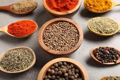 Photo of Different aromatic spices on gray textured table, closeup