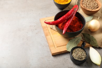 Photo of Different aromatic spices on gray textured table, closeup. Space for text