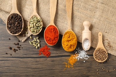 Photo of Different aromatic spices in spoons and scoop on wooden table, flat lay