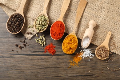 Photo of Different aromatic spices in spoons and scoop on wooden table, flat lay