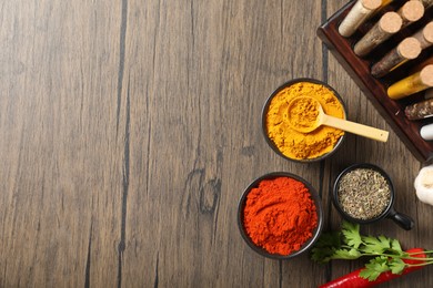 Photo of Different aromatic spices on wooden table, flat lay. Space for text