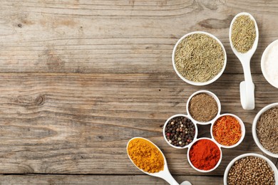 Photo of Different aromatic spices on wooden table, flat lay. Space for text
