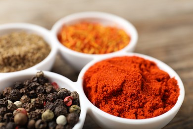 Photo of Different aromatic spices in bowls on table, closeup