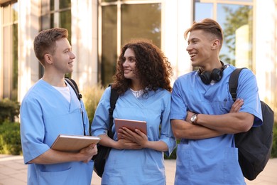 Photo of Happy medical students in uniforms near building outdoors