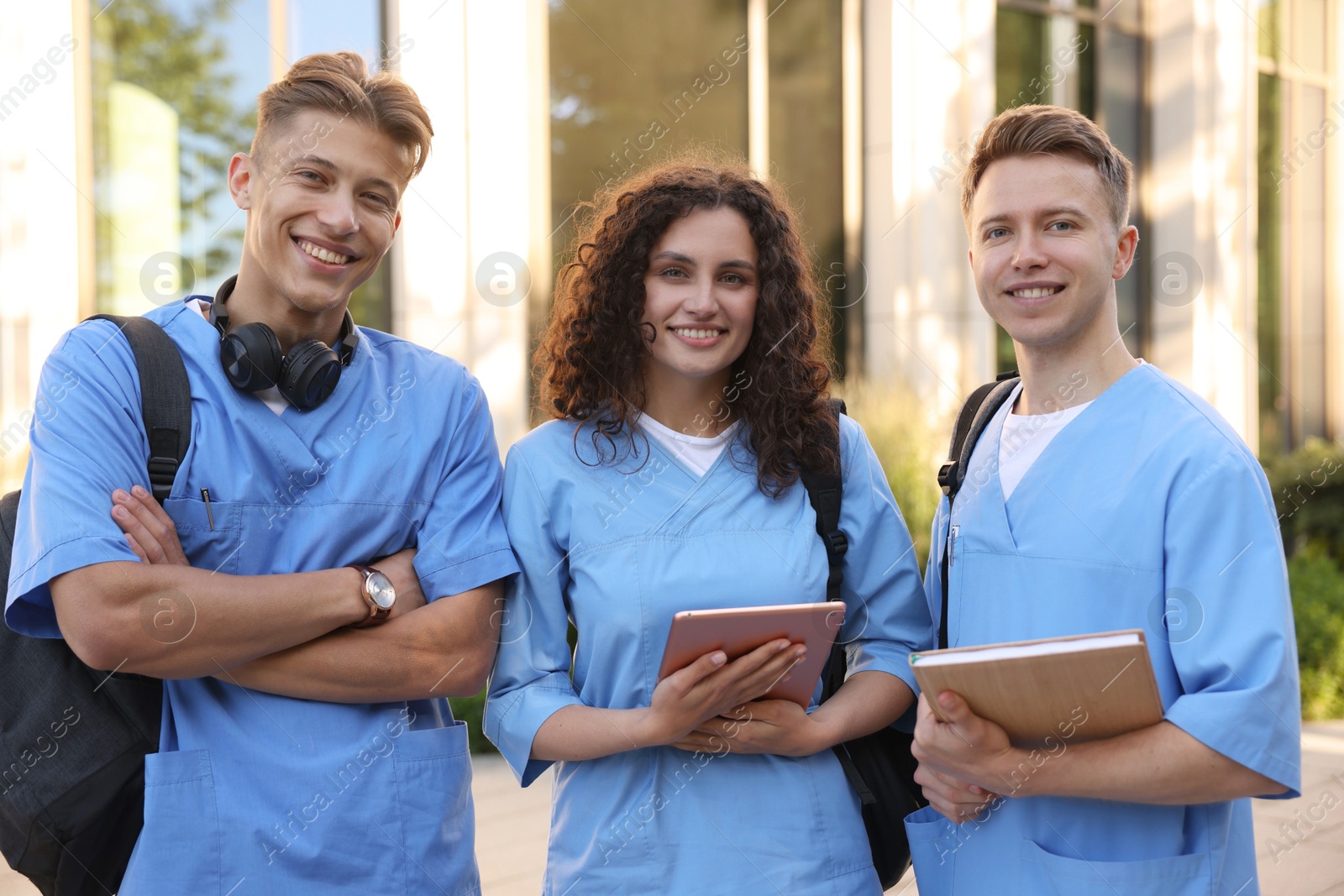 Happy medical students in uniforms near building outdoors Photo of Happy medical students in uniforms near building outdoors
