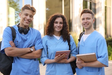 Photo of Happy medical students in uniforms near building outdoors