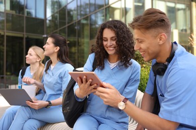 Photo of Group of medical students in uniforms studying together near building outdoors