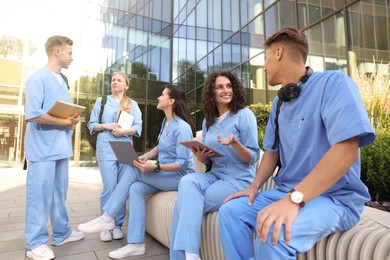 Photo of Group of medical students in uniforms studying together near building outdoors