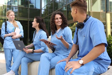 Photo of Group of medical students in uniforms studying together near building outdoors