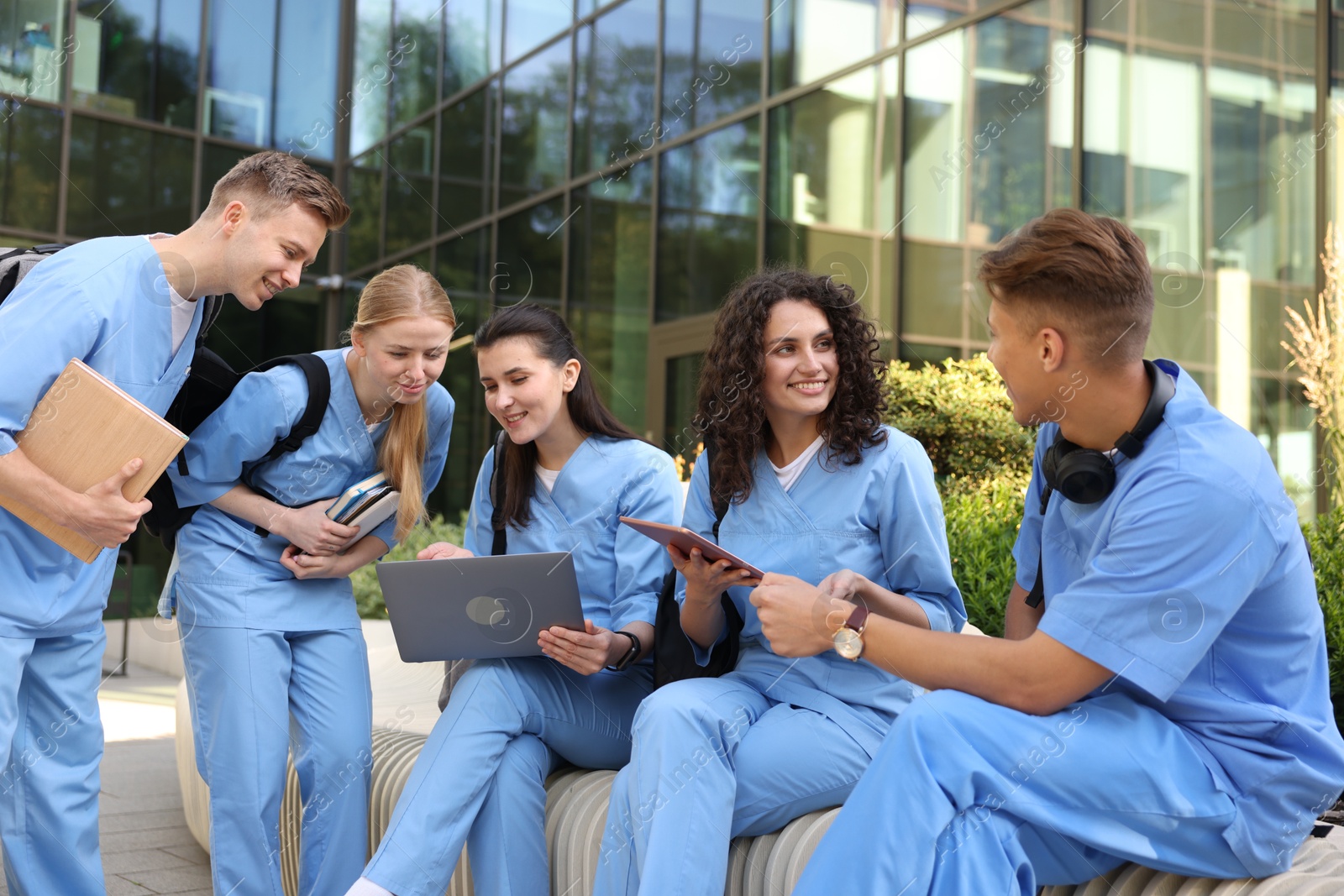 Photo of Group of medical students in uniforms studying together near building outdoors