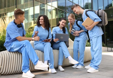 Photo of Group of medical students in uniforms studying together near building outdoors