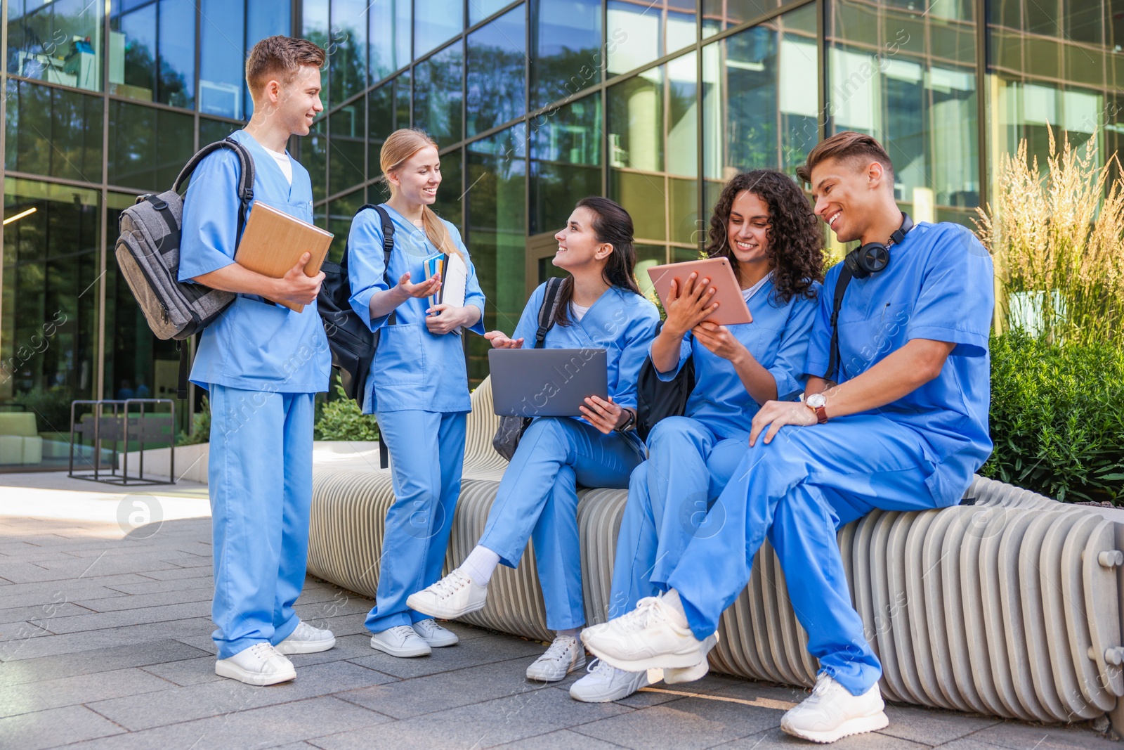 Photo of Group of medical students in uniforms studying together near building outdoors