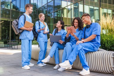 Photo of Group of medical students in uniforms studying together near building outdoors