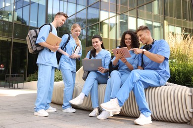 Photo of Group of medical students in uniforms studying together near building outdoors