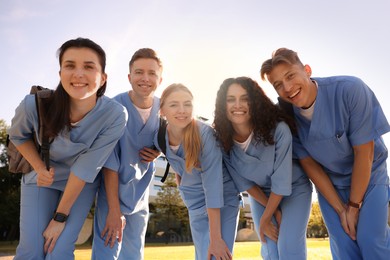 Photo of Group of medical students in uniforms with backpacks outdoors, low angle view