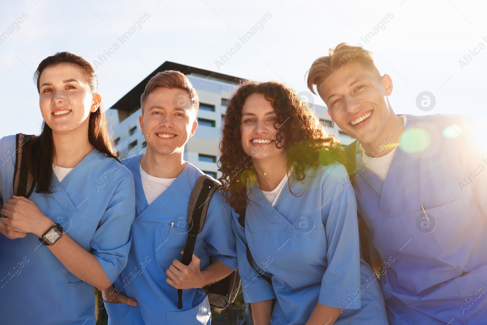 Group of medical students in uniforms with backpacks outdoors, low angle view Photo of Group of medical students in uniforms with backpacks outdoors, low angle view
