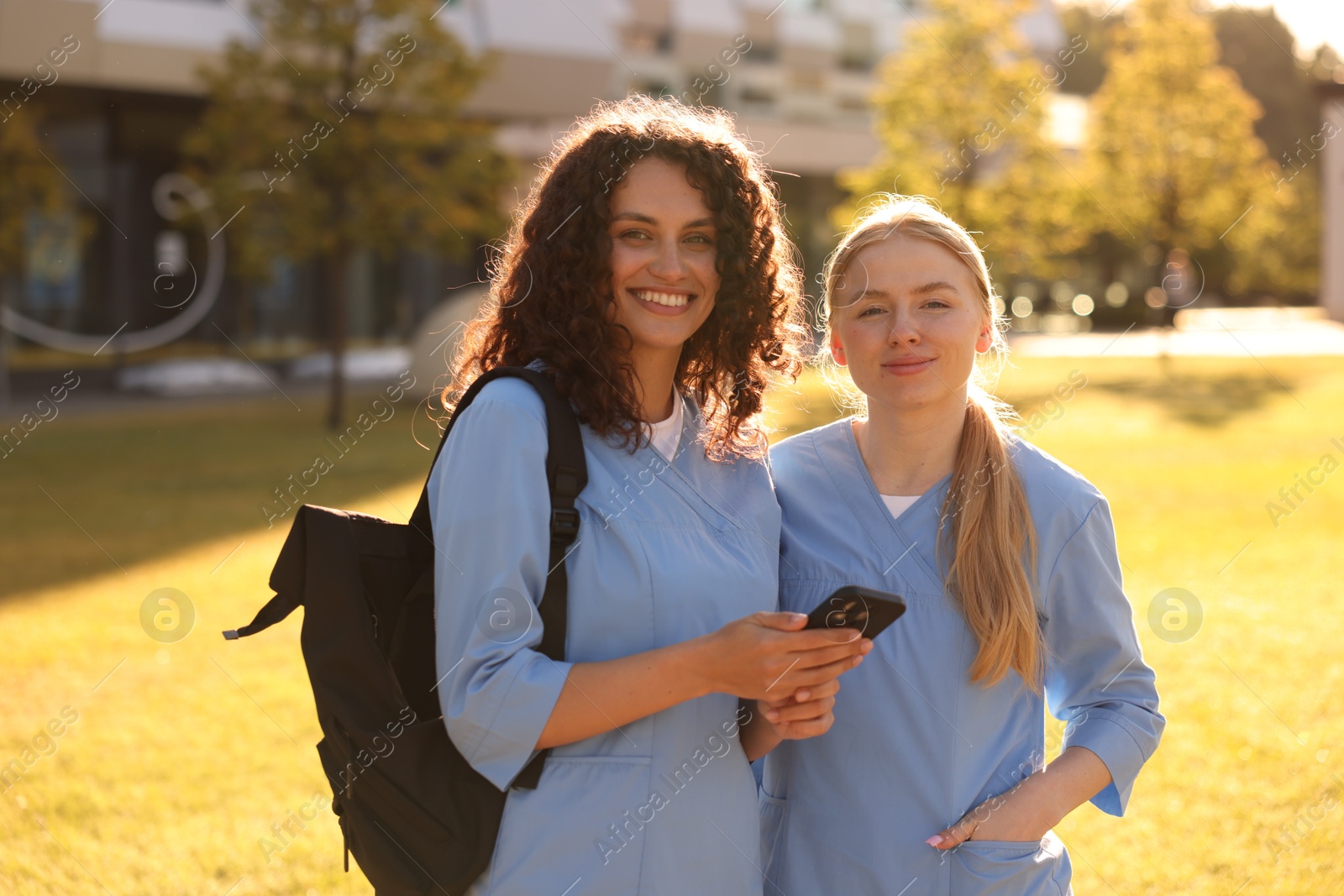 Medical students with smartphone outdoors on sunny day Photo of Medical students with smartphone outdoors on sunny day