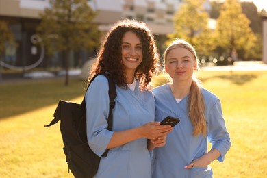 Photo of Medical students with smartphone outdoors on sunny day