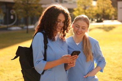Photo of Medical students with smartphone outdoors on sunny day