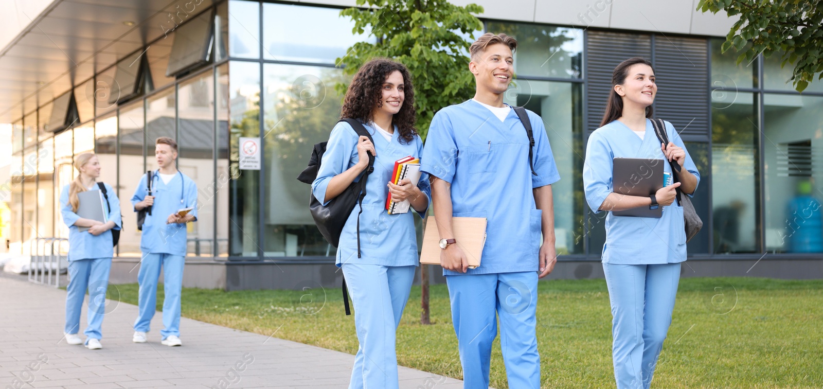Medical students in uniforms walking near building outdoors Photo of Medical students in uniforms walking near building outdoors