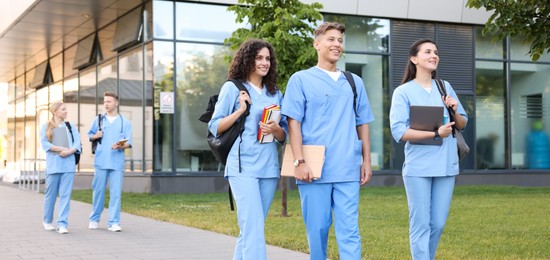 Photo of Medical students in uniforms walking near building outdoors
