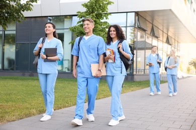 Photo of Medical students in uniforms walking near building outdoors