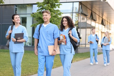 Photo of Medical students in uniforms walking near building outdoors