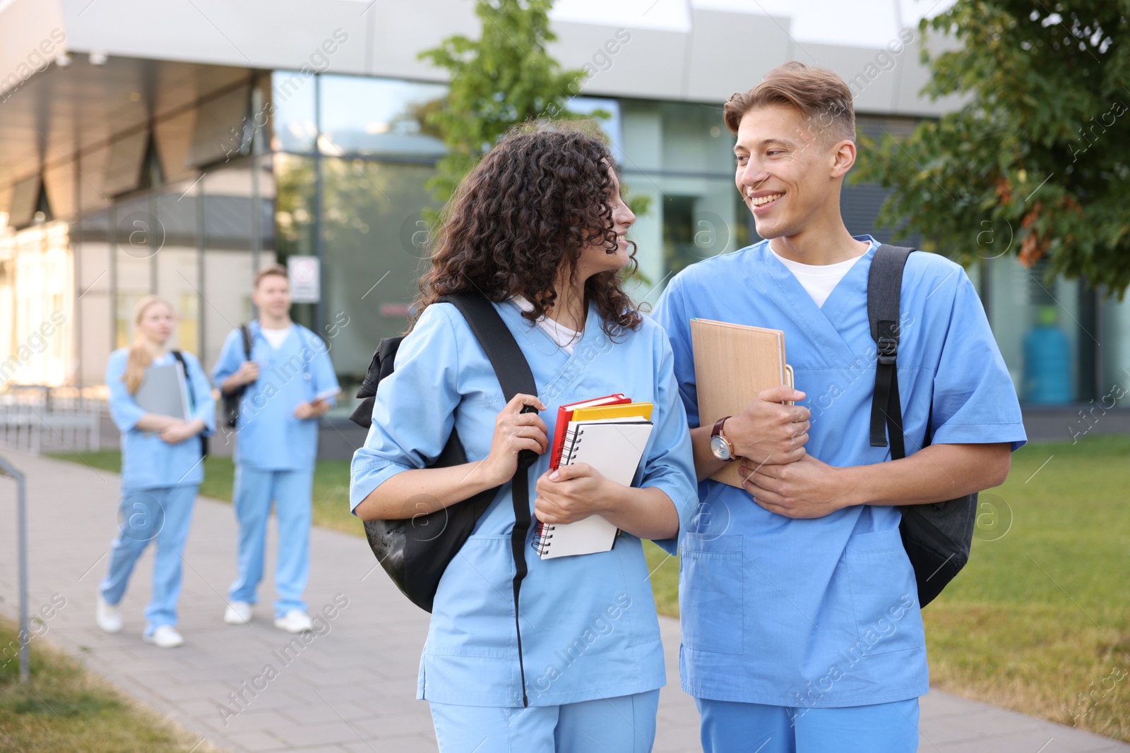 Photo of Medical students in uniforms with backpacks and notebooks outdoors, selective focus