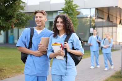Photo of Medical students in uniforms with backpacks and notebooks outdoors, selective focus