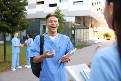 Photo of Medical students in uniforms spending time together outdoors, selective focus