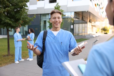 Photo of Medical students in uniforms spending time together outdoors, selective focus