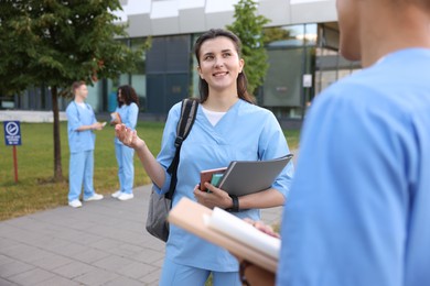 Photo of Medical students in uniforms spending time together outdoors, selective focus