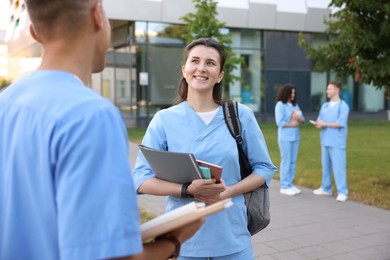 Photo of Medical students in uniforms spending time together outdoors, selective focus