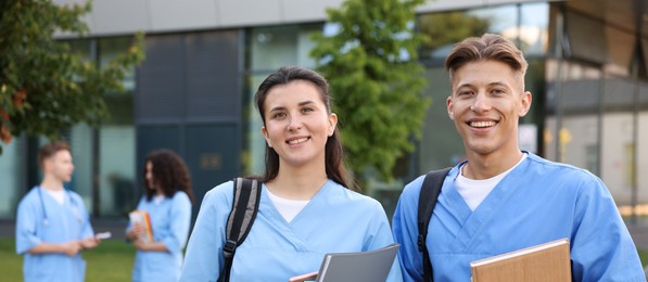 Photo of Medical students in uniforms with notebooks outdoors, selective focus