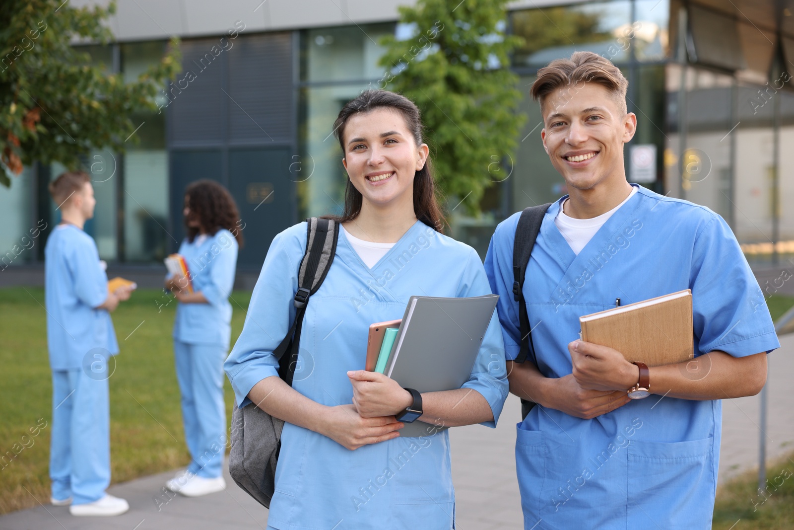Medical students in uniforms with notebooks outdoors, selective focus Photo of Medical students in uniforms with notebooks outdoors, selective focus