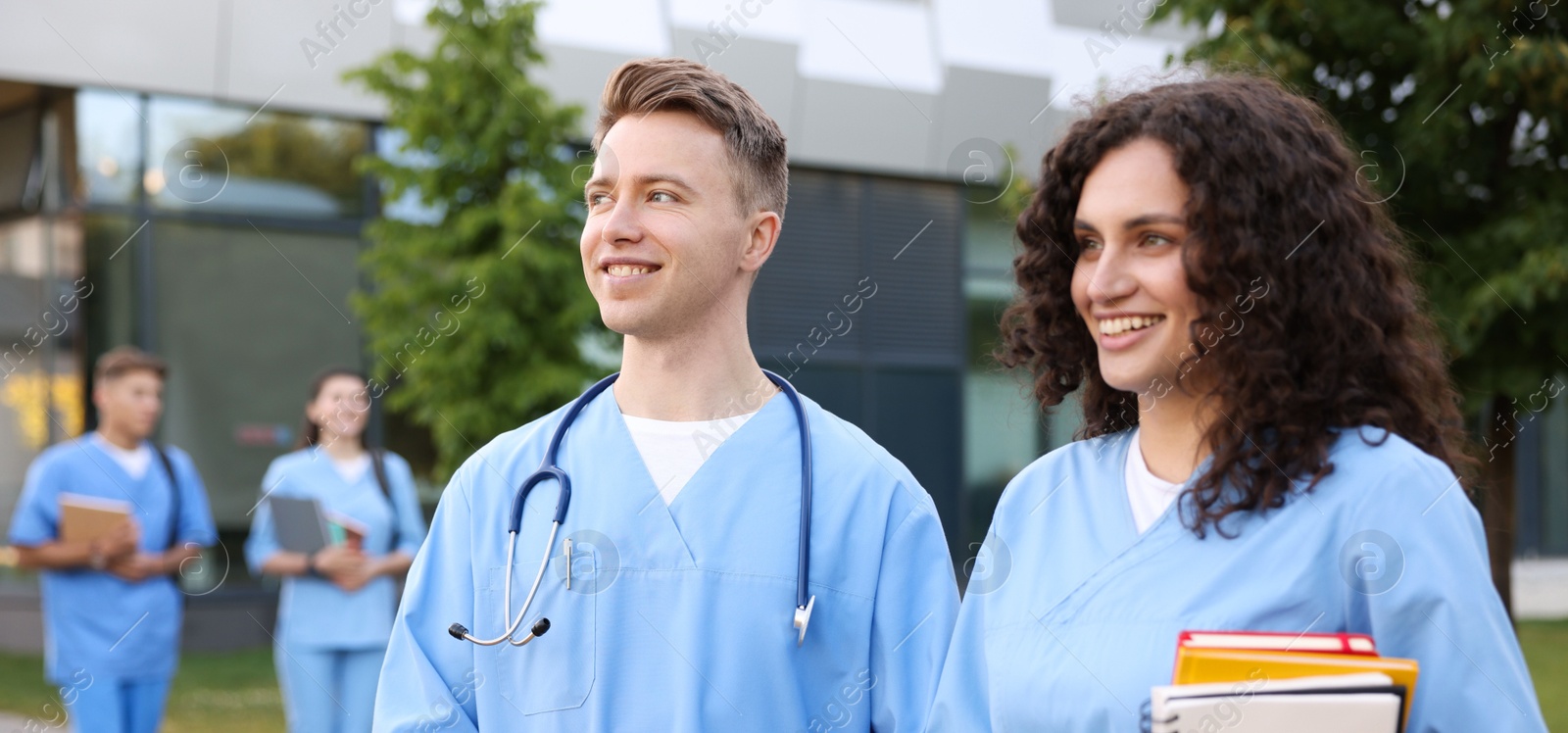 Medical students in uniforms with notebooks outdoors, selective focus Photo of Medical students in uniforms with notebooks outdoors, selective focus