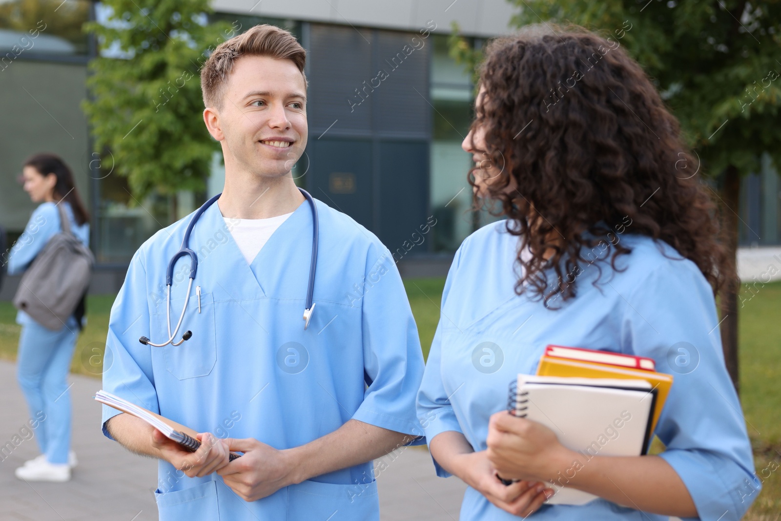Medical students in uniforms with notebooks outdoors, selective focus Photo of Medical students in uniforms with notebooks outdoors, selective focus
