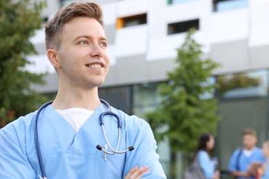 Photo of Medical student in uniform with stethoscope outdoors, selective focus. Space for text