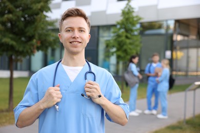 Photo of Medical student in uniform with stethoscope outdoors, selective focus